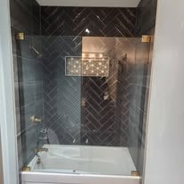 Herringbone tile shower surround with brushed brass fixtures.