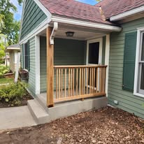 Rebuilt front porch with cedar posts, railing and fresh concrete pad.